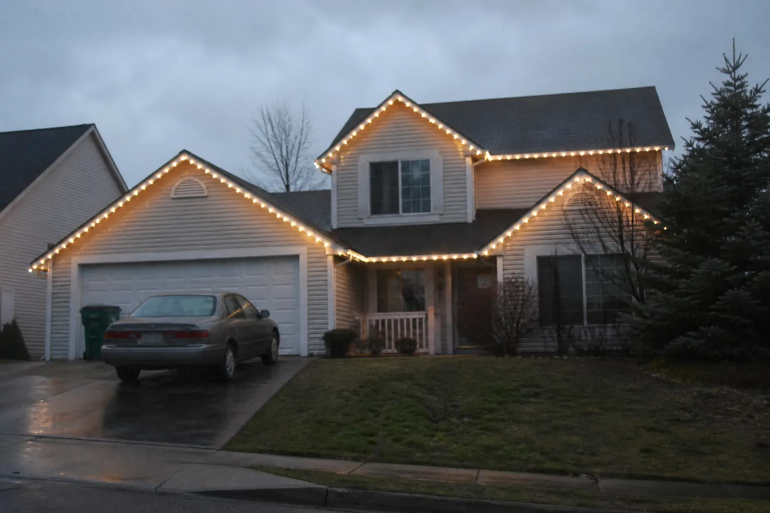 A two-storey home at dusk with every gable, dormer and eave outlined in evenly spaced warm-white C9 bulbs