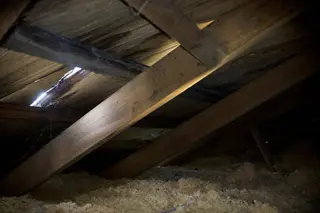 The underside of a roof deck seen from inside an attic, with rafters and insulation visible
