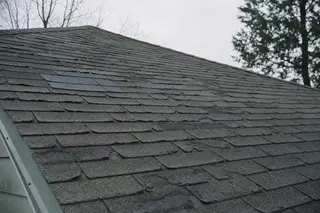 An aging asphalt shingle roof showing curling edges and patches of lost granules